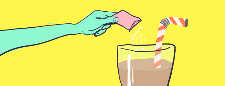 Hand holding a packet of artificial sweetener over a glass containing a beverage with a red and white straw.