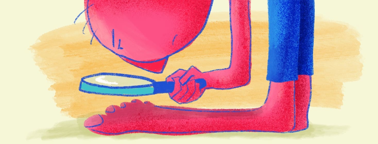 person looking at their feet with a magnifying glass