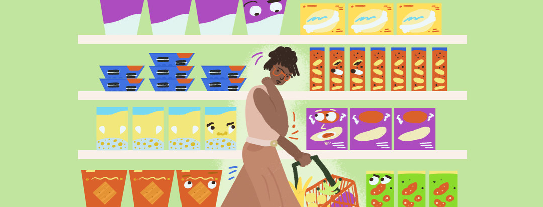 Woman holding a grocery basket is in the middle of an aisle of snack foods. Some of the boxes of treats have eyes that are staring at her.