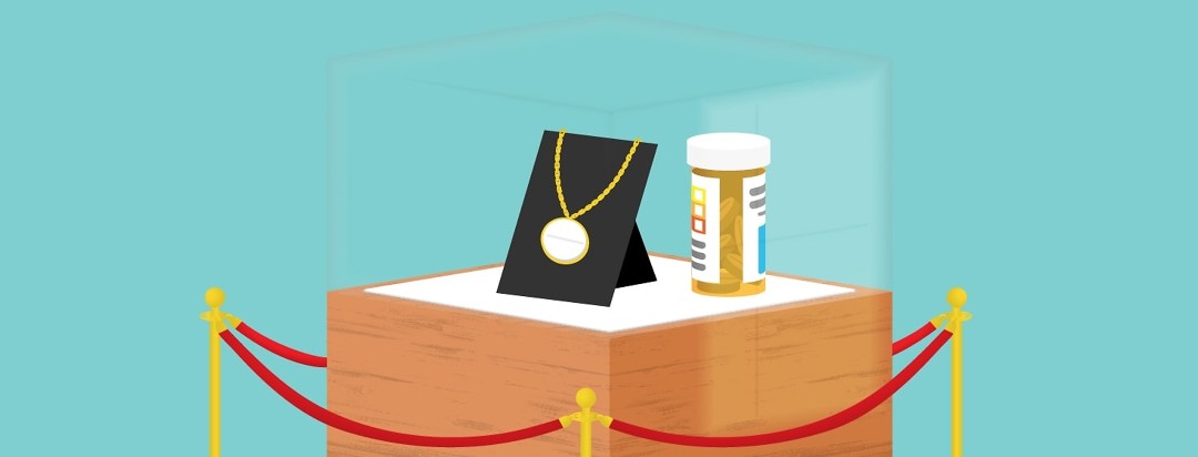 a pill in a necklace in a glass case behind velvet ropes
