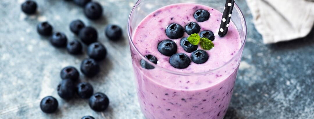 Blueberry smoothie topped with fresh blueberries and a mint garnish.