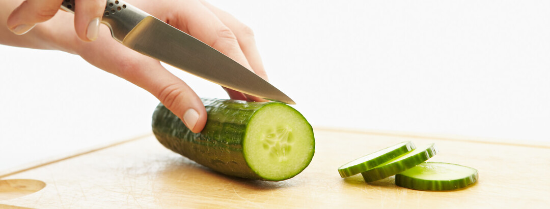Cucumber being cut for a mango cucumber salad