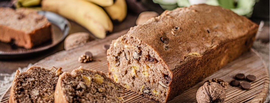 loaf of banana bread surrounded by walnuts and chocolate chips.