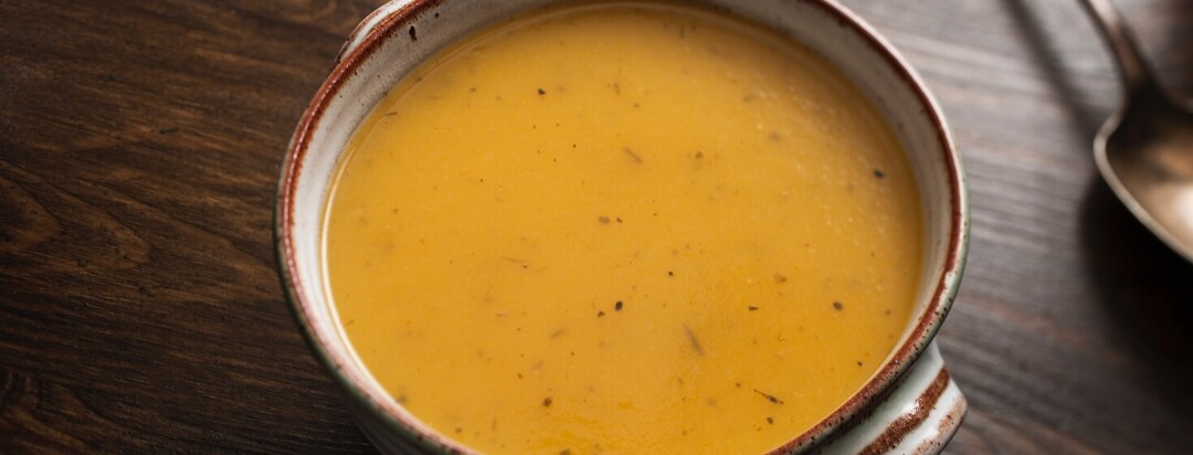 Bowl of Butternut Squash Soup against a dark wood table.