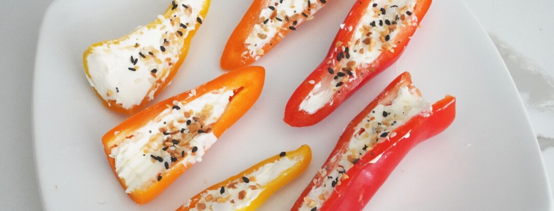 Cream cheese stuffed peppers on a white plate sprinkled with seasoning