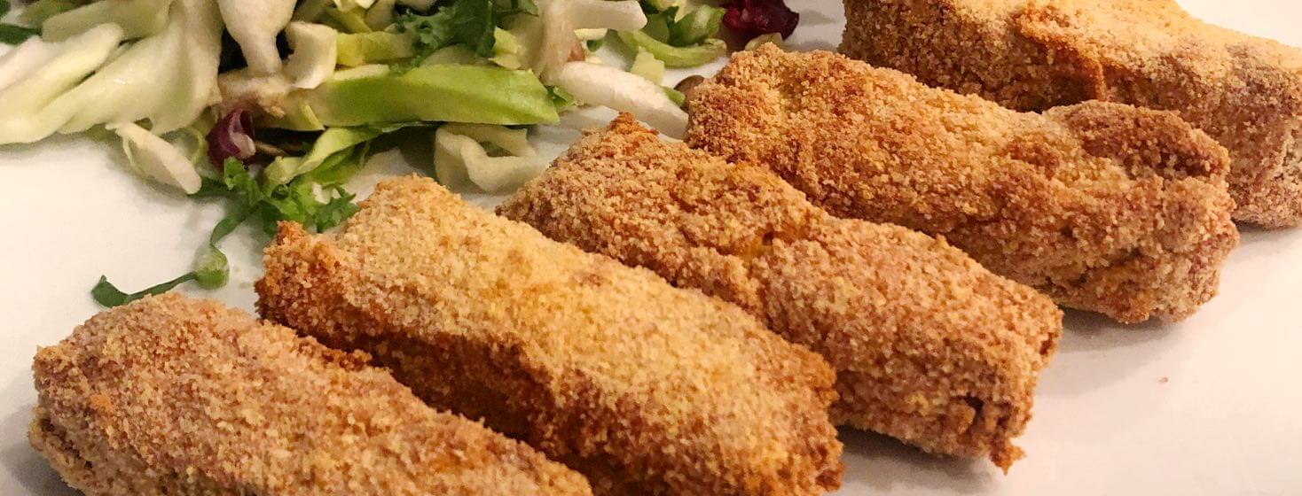 Tempeh tenders with Tzatziki sauce and salad on a plate.