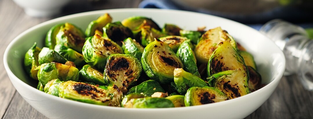 Roasted Brussels sprouts in a white bowl on a wooden table