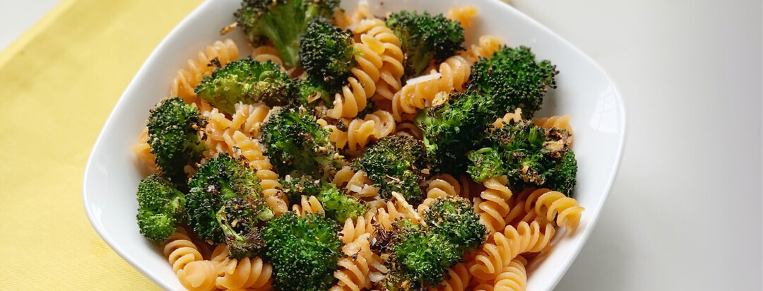 Bowl of crispy broccoli and butter noodles on table