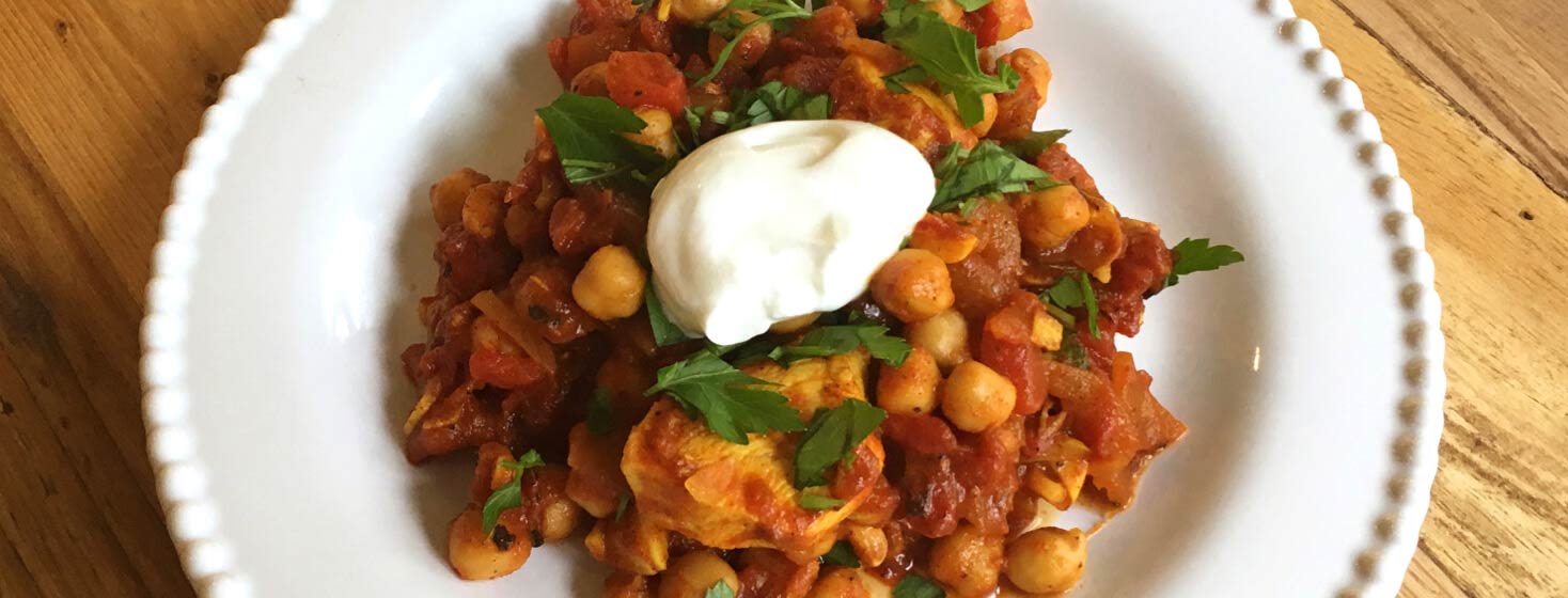 Plate of chicken chickpea tagine on a dining table.