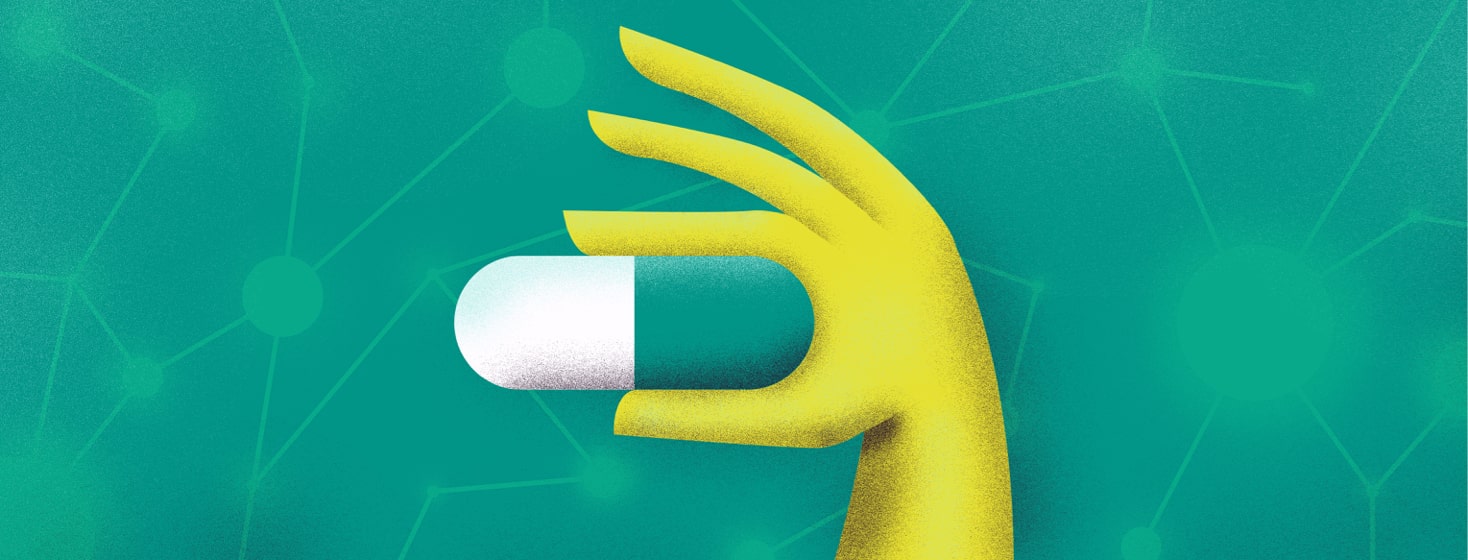 a hand holding a pill